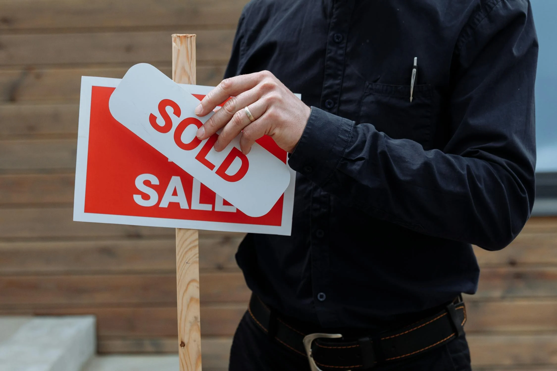 sold sticker being placed on a for sale sign